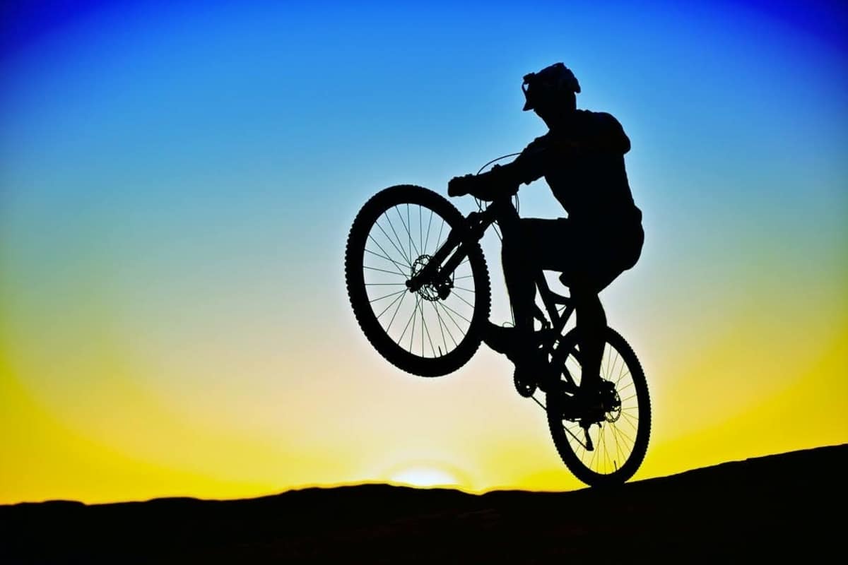 silhouette of a mountain biker doing a wheelie